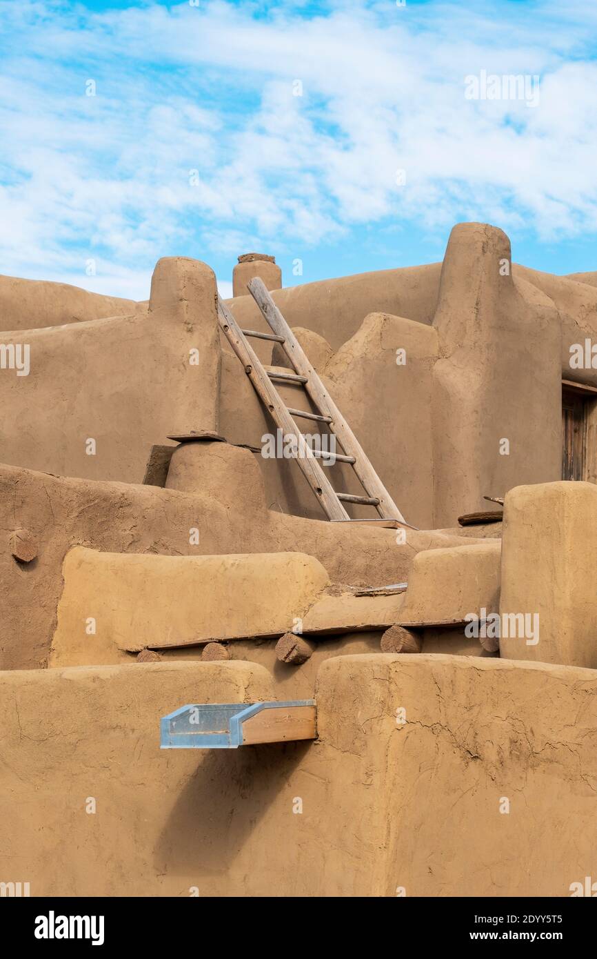 A handmade wooden ladder leading to the roof of an adobe house in the Native American adobe village of Taos Pueblo, New Mexico, USA. A UNESCO World He Stock Photo
