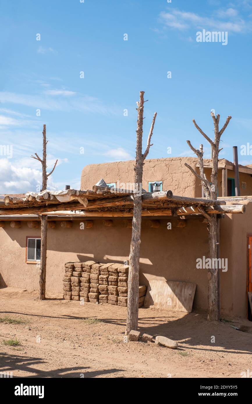 Adobe mud bricks piled up beside an adobe house in the historical Native American village of Taos Pueblo, New Mexico, USA. A UNESCO World Heritage Sit Stock Photo