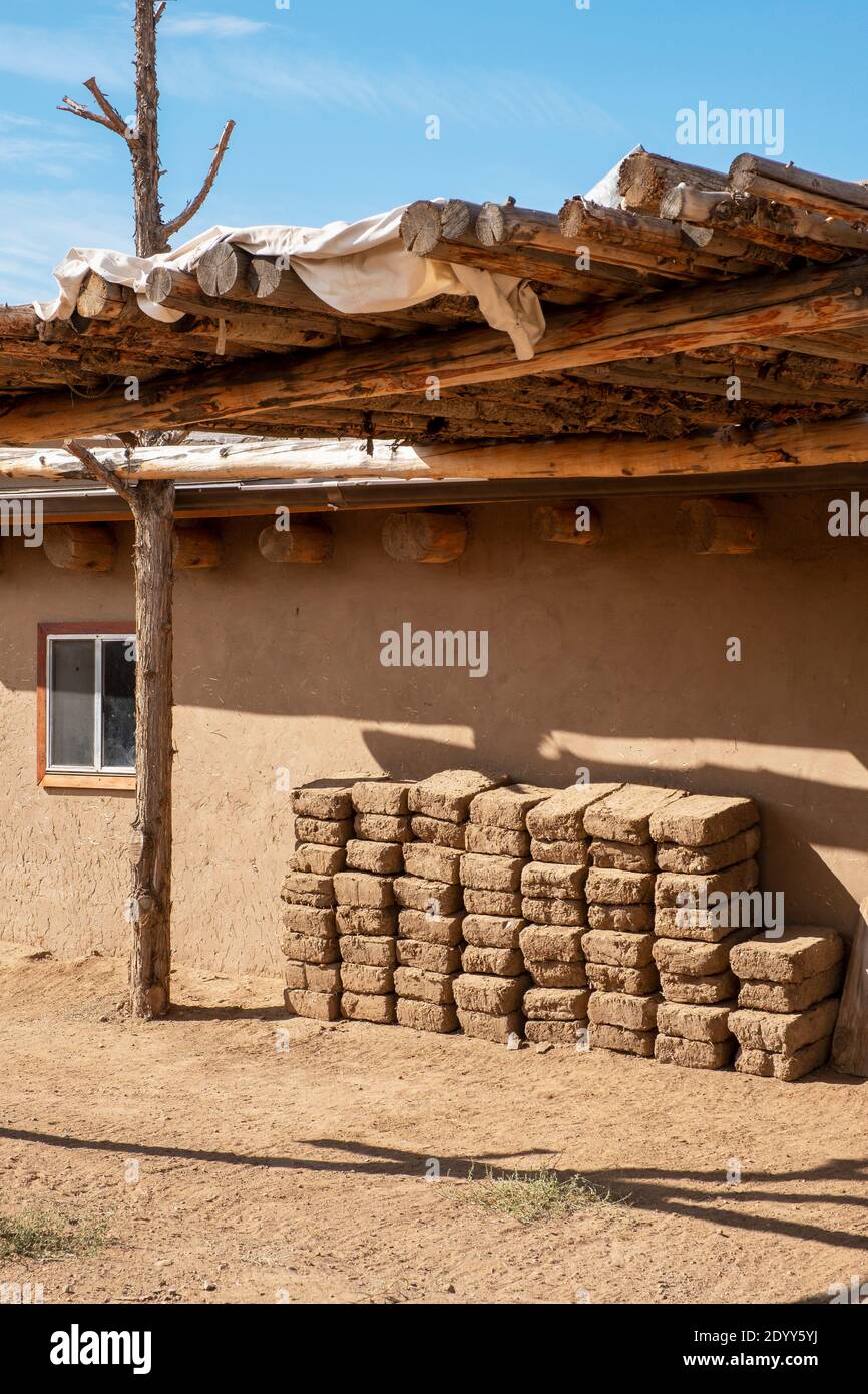 Adobe mud bricks piled up beside an adobe house in the historical Native American village of Taos Pueblo, New Mexico, USA. A UNESCO World Heritage Sit Stock Photo