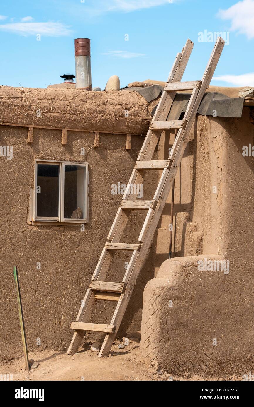 A wooden ladder leads to the roof of an adobe house in the Native American village of Taos Pueblo, New Mexico, USA. A UNESCO World Heritage Site. Stock Photo