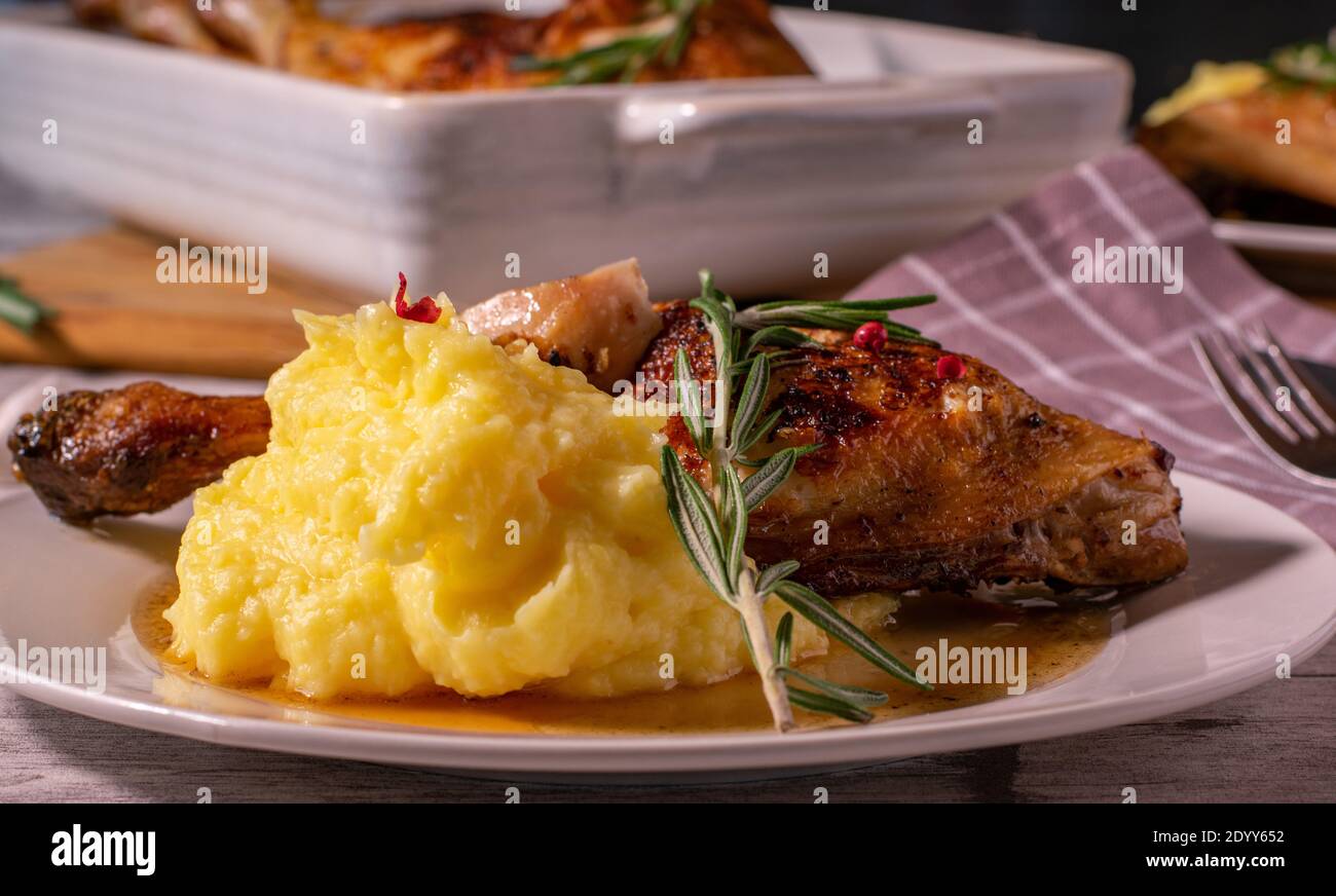 Mashed potatoes on a white plate with chicken and rosemary butter sauce. Stock Photo