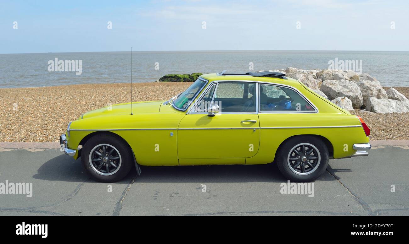 Classic Yellow MGB GT parked on seafront promenade. Stock Photo