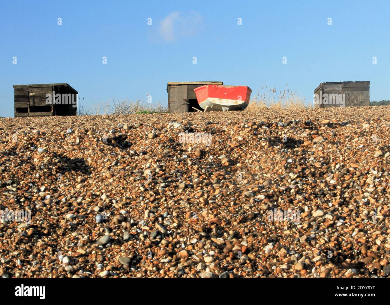 Fishing boat and huts on the beach at Dunwich, Suffolk Stock Photo