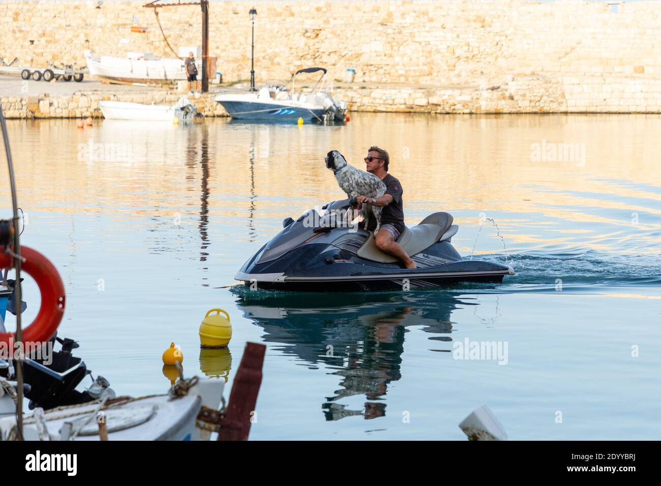 A man and a dog on jetski at the Old Venetian Harbour, Rethymno, Crete, Greece Stock Photo