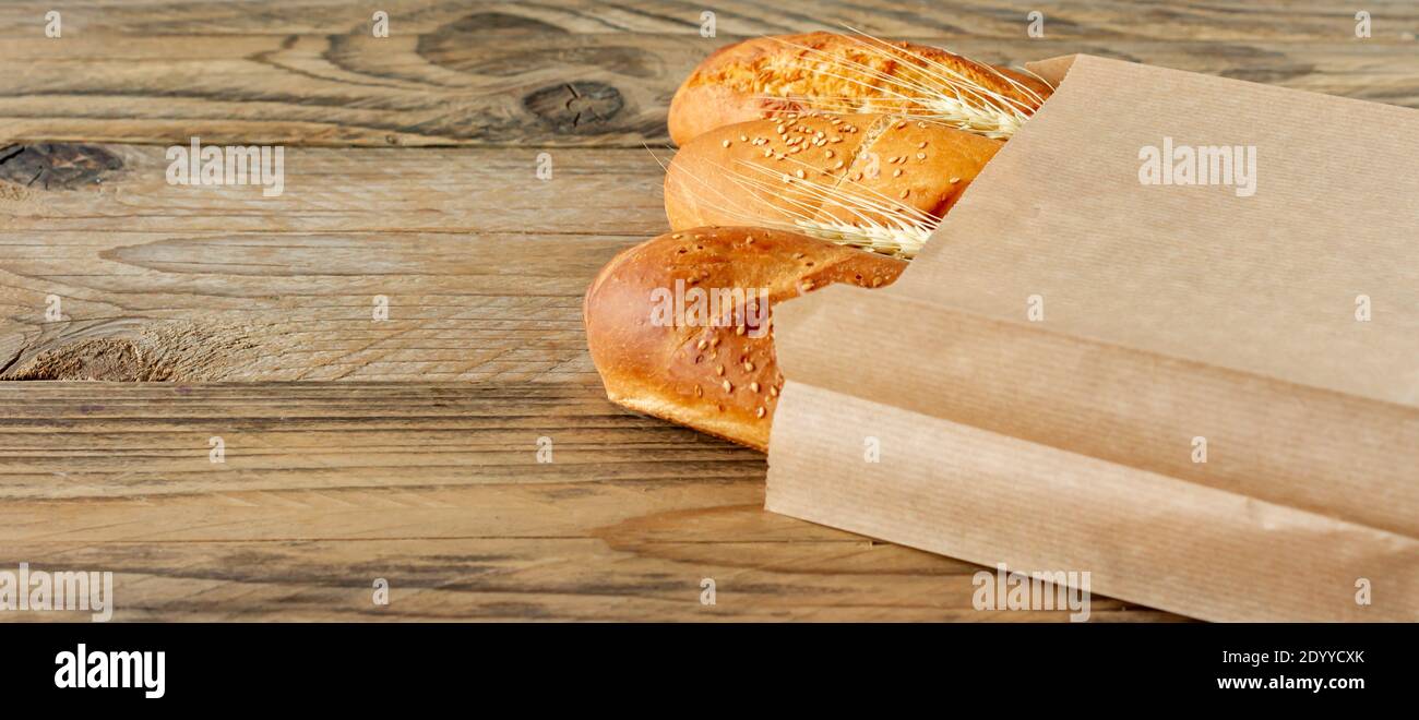 arranged french baguettes in paper bag and wheat on rustic wooden ...