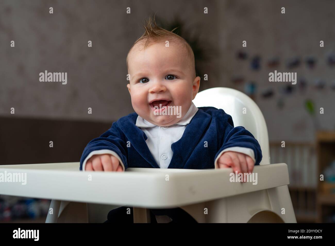 baby boy sitting in a white high chair and smiling Stock Photo