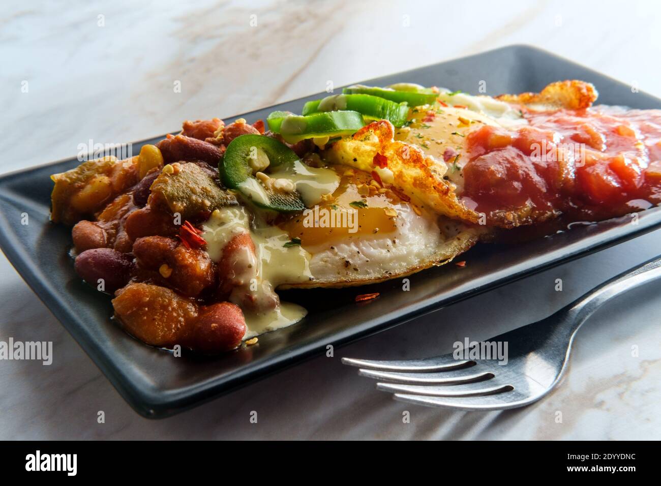 Two Mexican fried eggs with salsa chili and sliced jalapeno served huevos rancheros style Stock