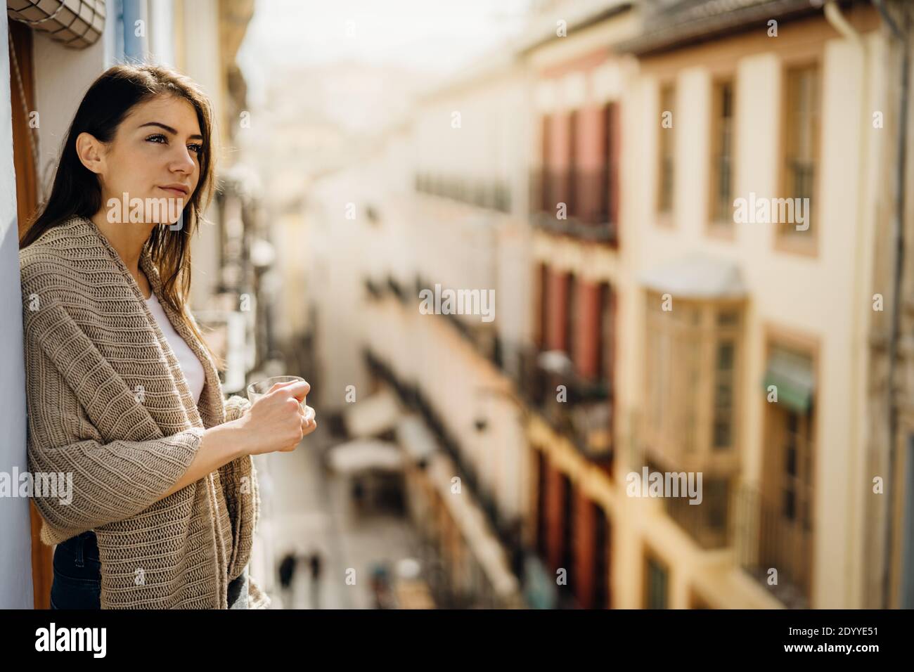 Young woman spending free time home.Self care,staying home.Enjoying view from the balcony.Quarantined person indoors.Serene mornings.Avoiding social c Stock Photo