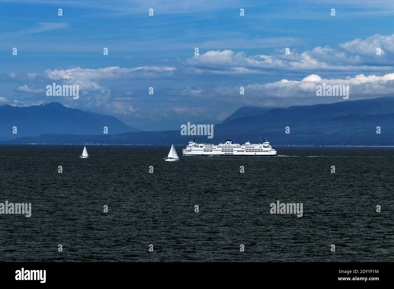 Sail boats and the giant ferry on the Pacific Ocean, BC, Canada. Pacific ocean borders Western Canada. British Columbia's coastal weather is shaped by Stock Photo