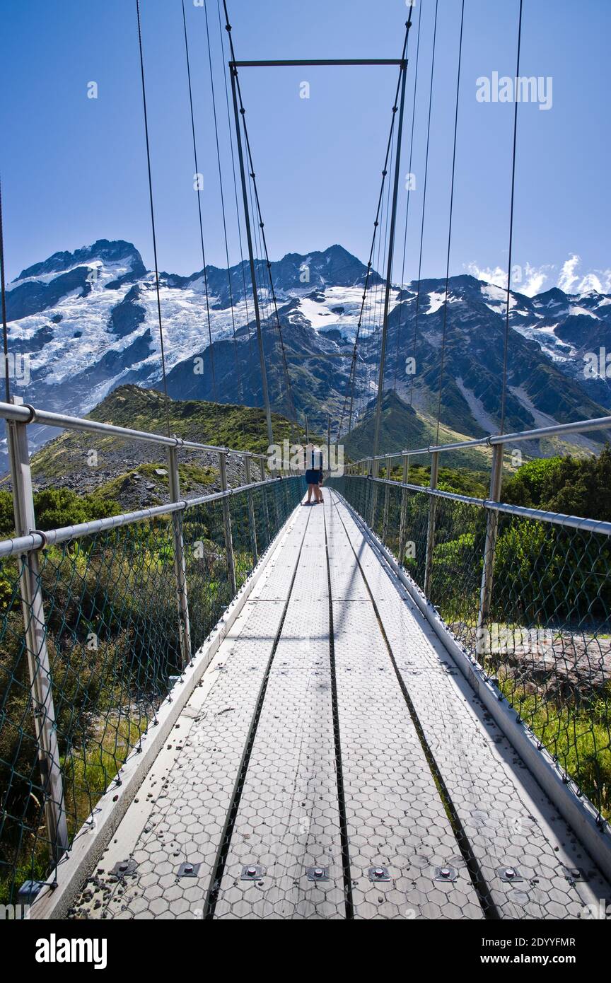 Tourist walkers admire the view from the second swing bridge on the Hooker Valley trail in Mt Cook National Park, New Zealand. Stock Photo