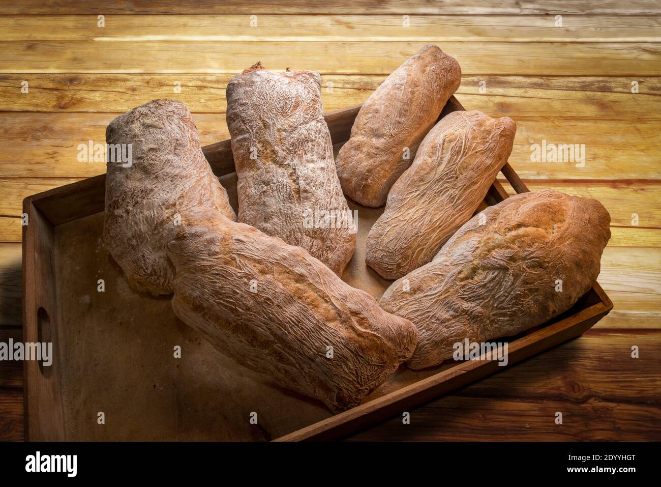 Italian ciabatta bread, six loaves in wooden tray on rustic wooden Stock Photo