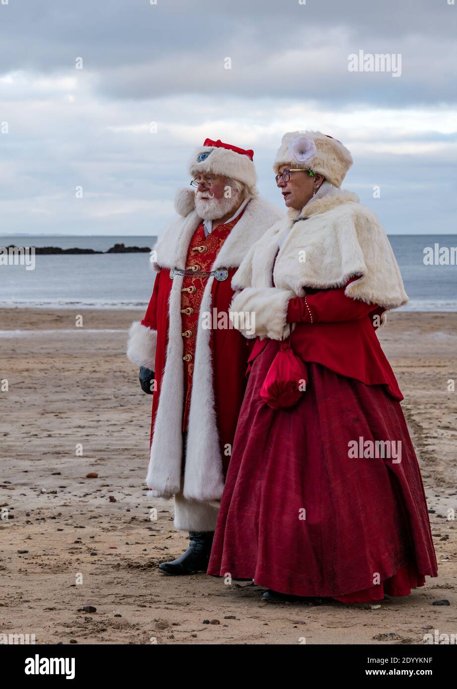 Couple dressed in Santa or Father Christmas and Mrs Claus costumes on beach, North Berwick, East Lothian, Scotland, UK Stock Photo