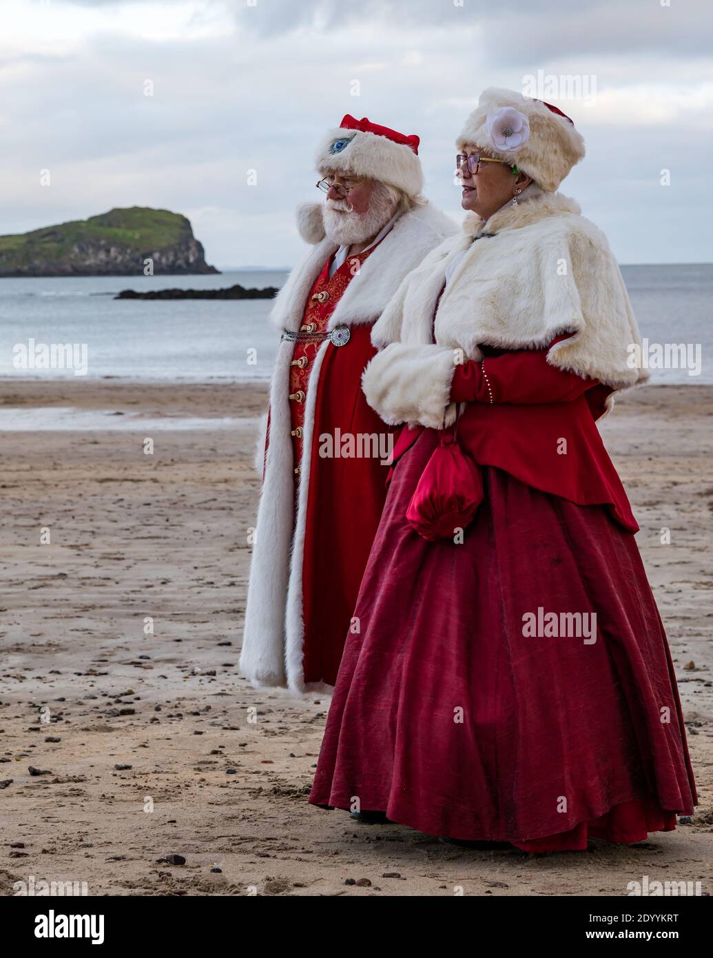 Couple dressed in Santa or Father Christmas and Mrs Claus costumes on beach, North Berwick, East Lothian, Scotland, UK Stock Photo