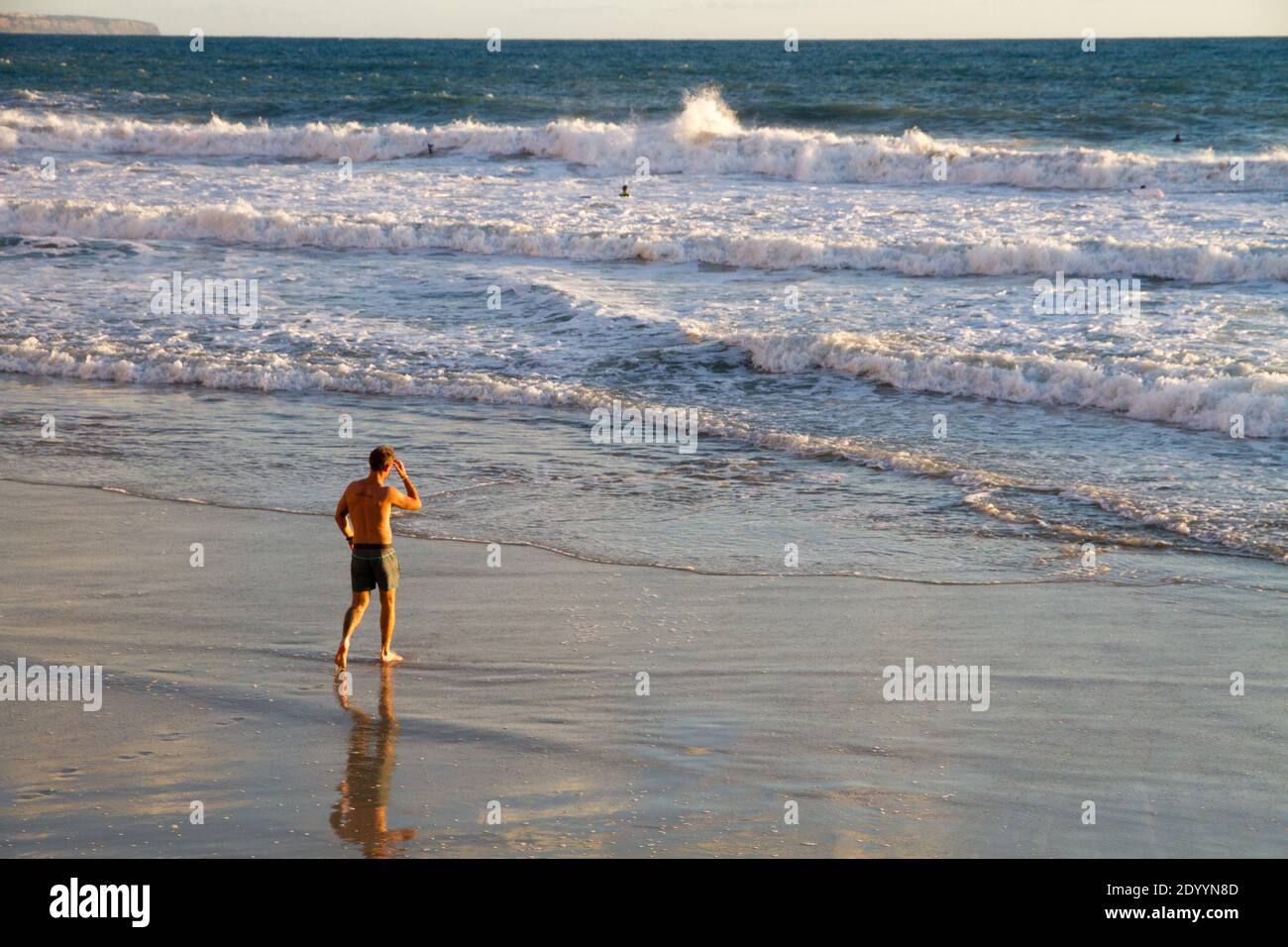 Post Covid lockdown, man wets his feet in sea water, Mallorca Spain Stock Photo