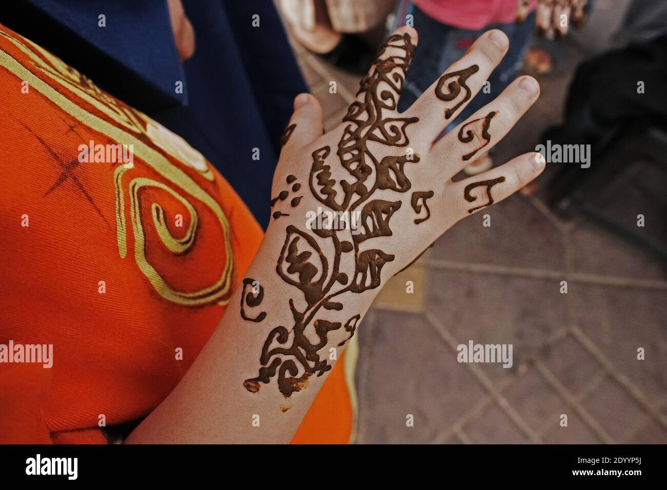 Female in an orange dress with a henna tattoo on her hand in  Morocco ,Marrakesh , North Africa. Stock Photo