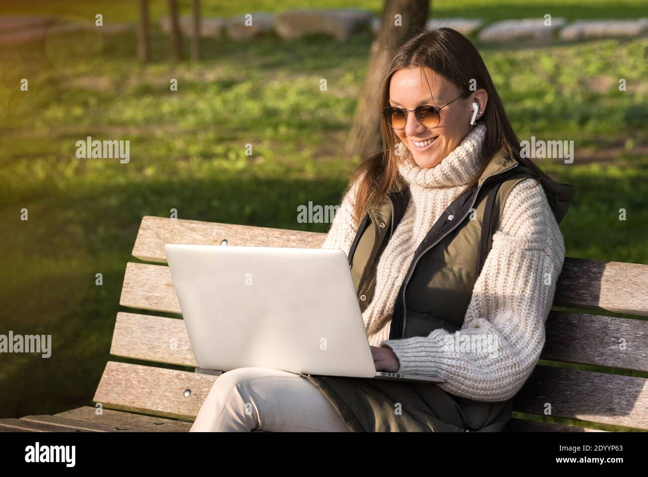 Happy woman working with laptop outdoor in city park. Freelance working concept Stock Photo