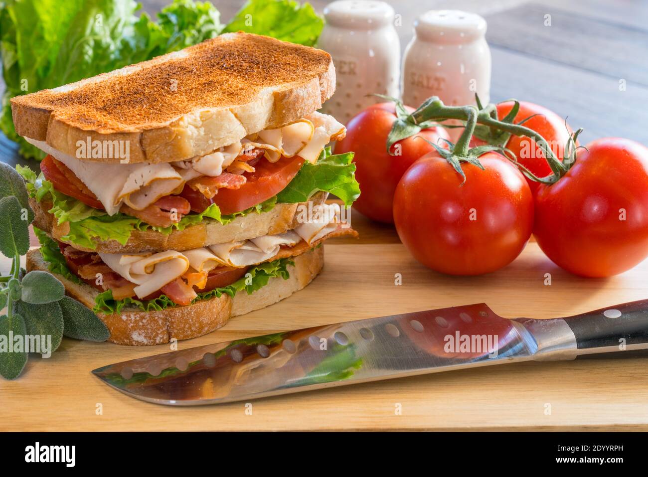 Fresh turkey club sandwich on white toast on a wooden cutting board Stock Photo