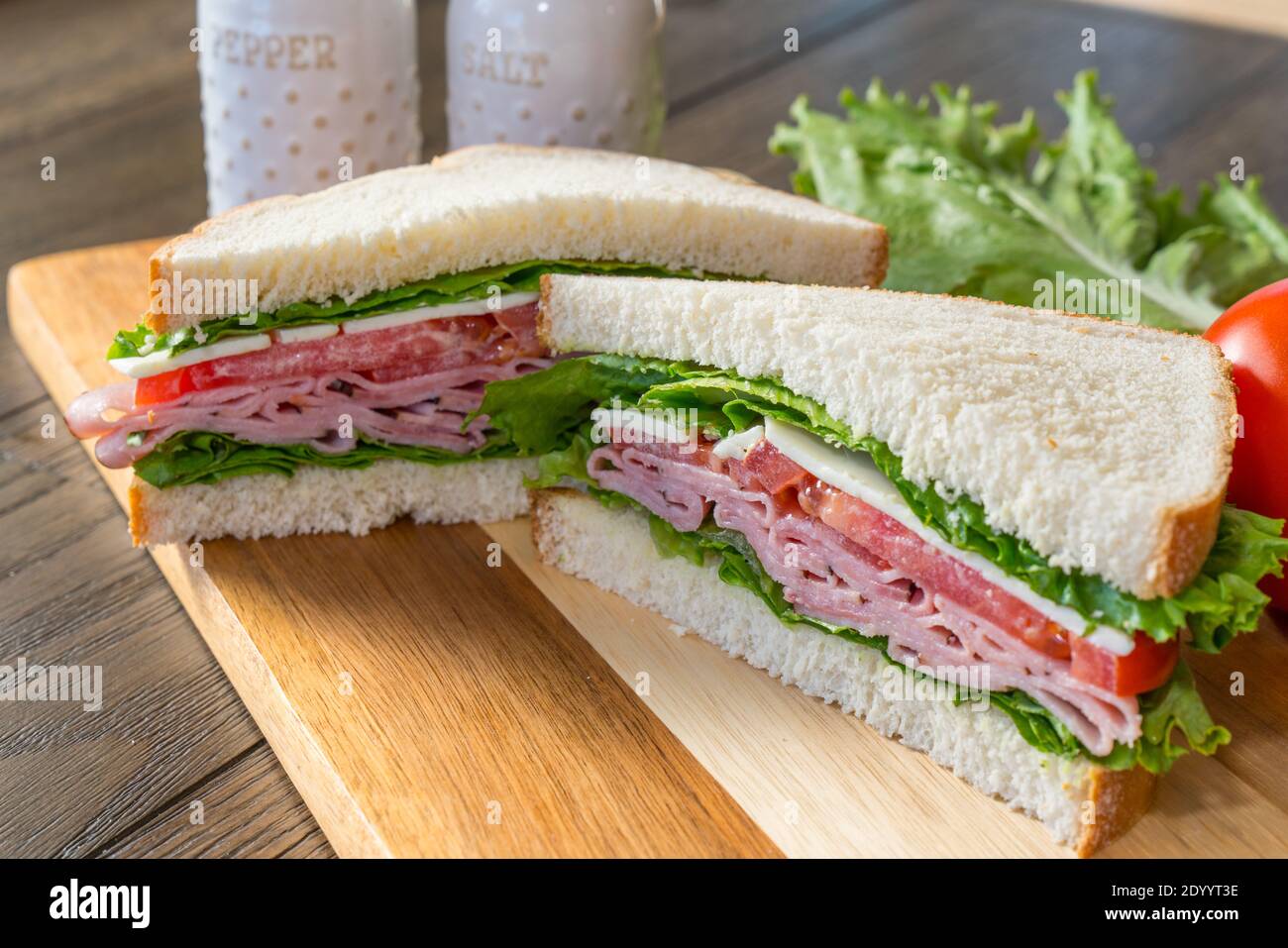 Fresh ham, tomato and cheese sandwich on cutting board Stock Photo