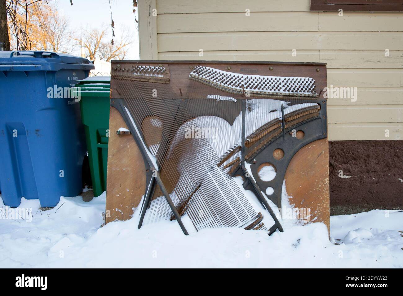 Snow covered old vintage upright piano soundboard in the alley awaiting garbage and solid waste removal Stock Photo