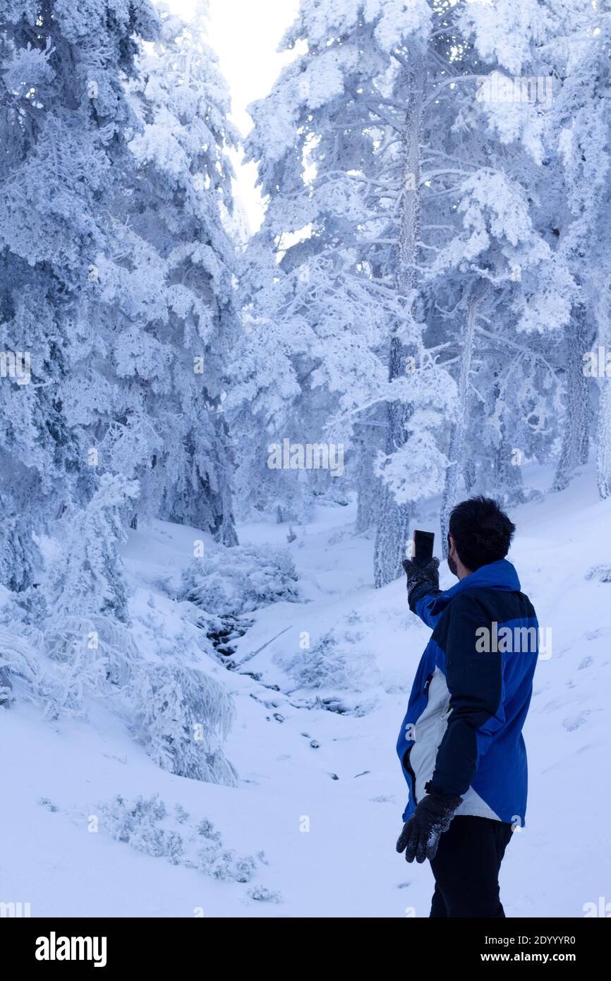 a middle-aged man searches for wifi signal on a snowy mountain. wifi connection in deep nature . Stock Photo