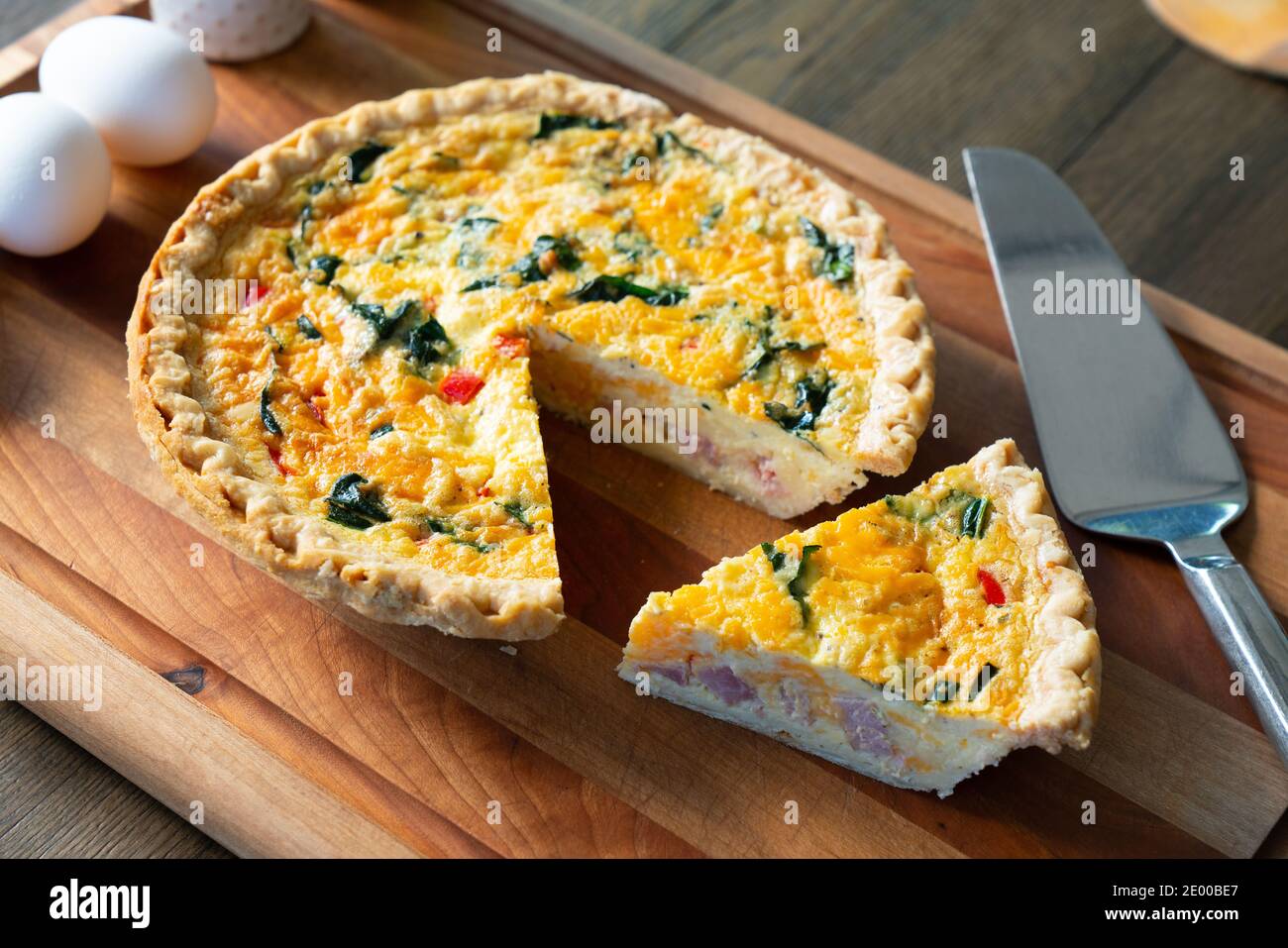 Freshly sliced quiche lorraine on cutting board Stock Photo