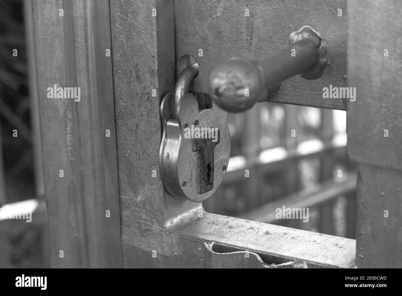 Padlock and bars. Concept for national lock down and restrictions. Monochrome image. Stock Photo