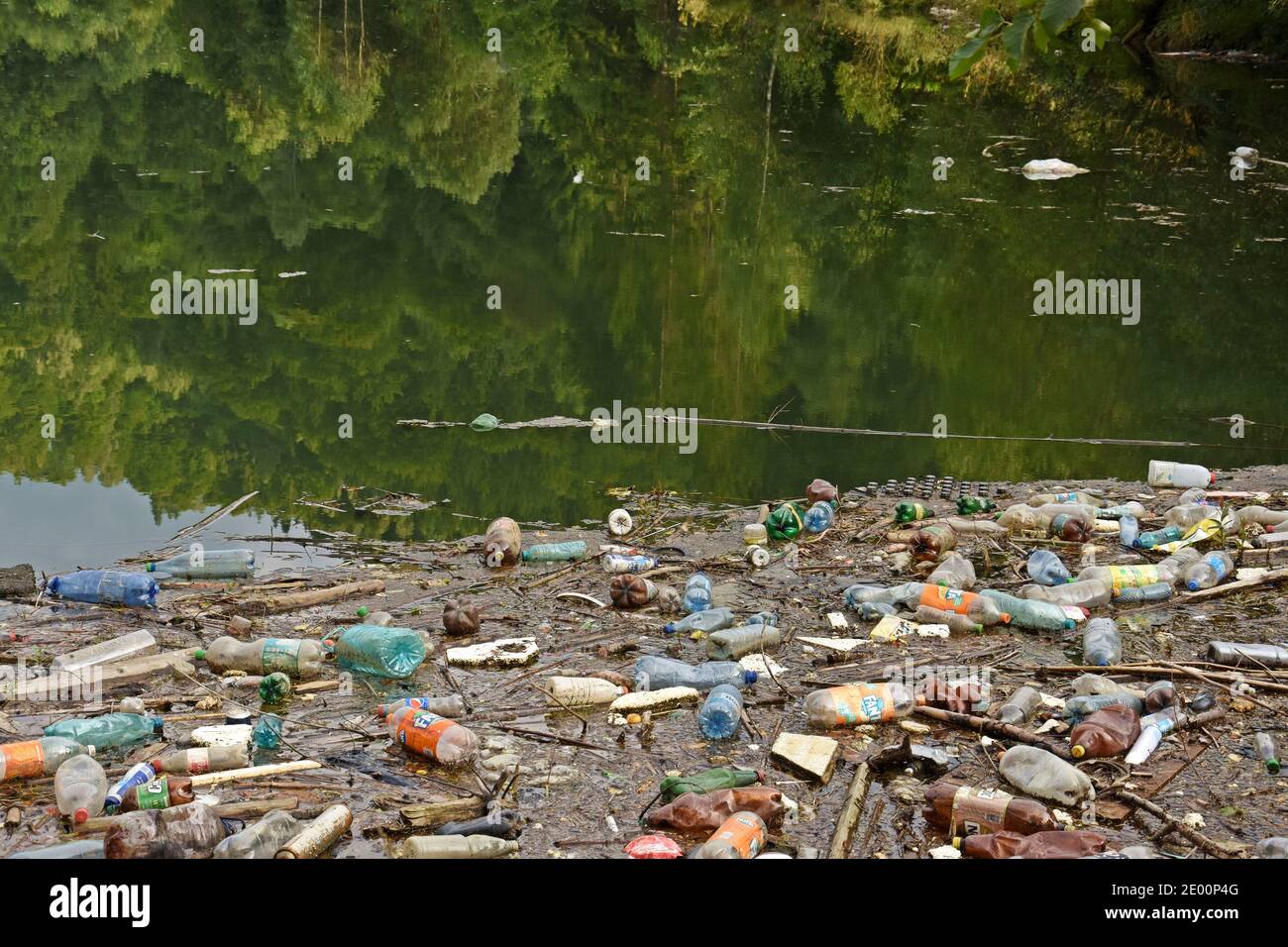 Environment pollution. Lake with plastic bottles and garbage in the mountains. Stock Photo