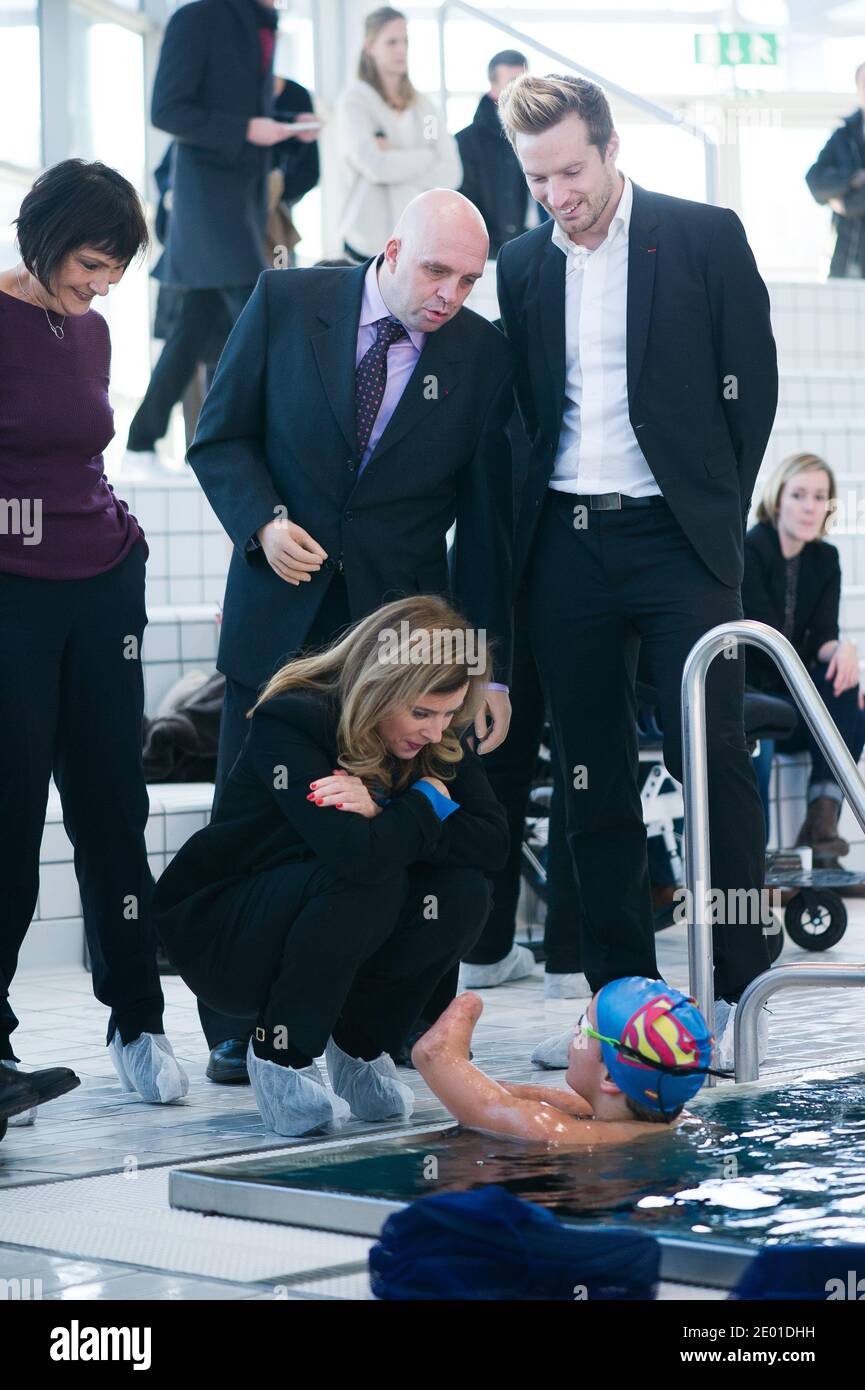 Companion of France's President Valerie Trierweiler and French Junior Minister for Disabled People Marie-Arlette Carlotti talk with next to Theo, a 13-year-old 4-limb amputee, standing in a pool, as part of their visit on November 27, 2013 in Vichy, central France. Theo is a grant holder of the disabled sports branch of the French Expertise and Performance Ressource Centre (CREPS) of Vichy Auvergne, where he trains in swimming. In early 2013, he competed for the first time in the French disabled swimming championships. At left is seen French Handisports Federation President Gerard Masson. Phot Stock Photo