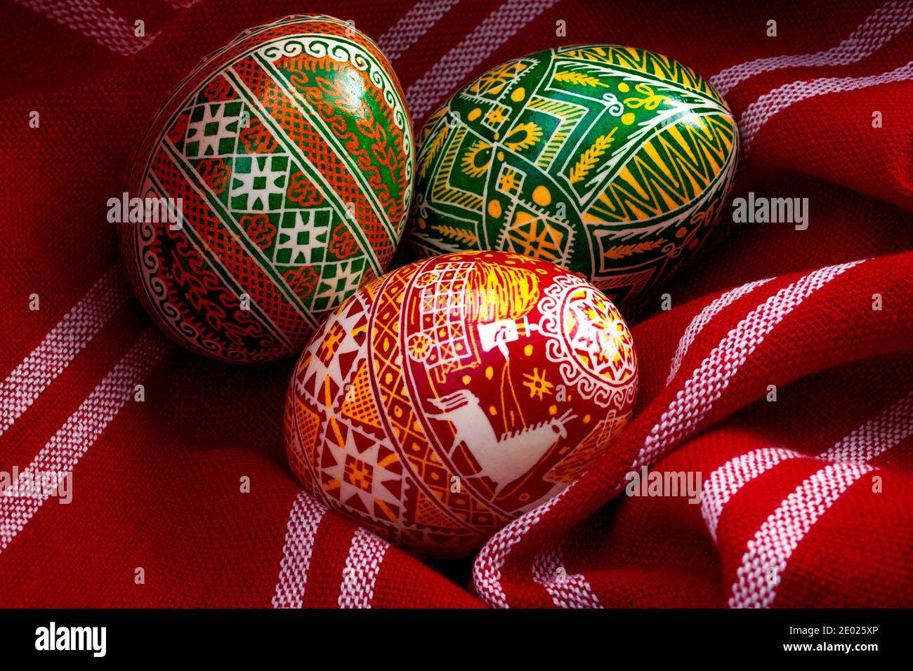 Spring holiday, natural ingredients and happy easter concept with three dyed eggs in a rustic vintage red cloth with each egg having different complex Stock Photo