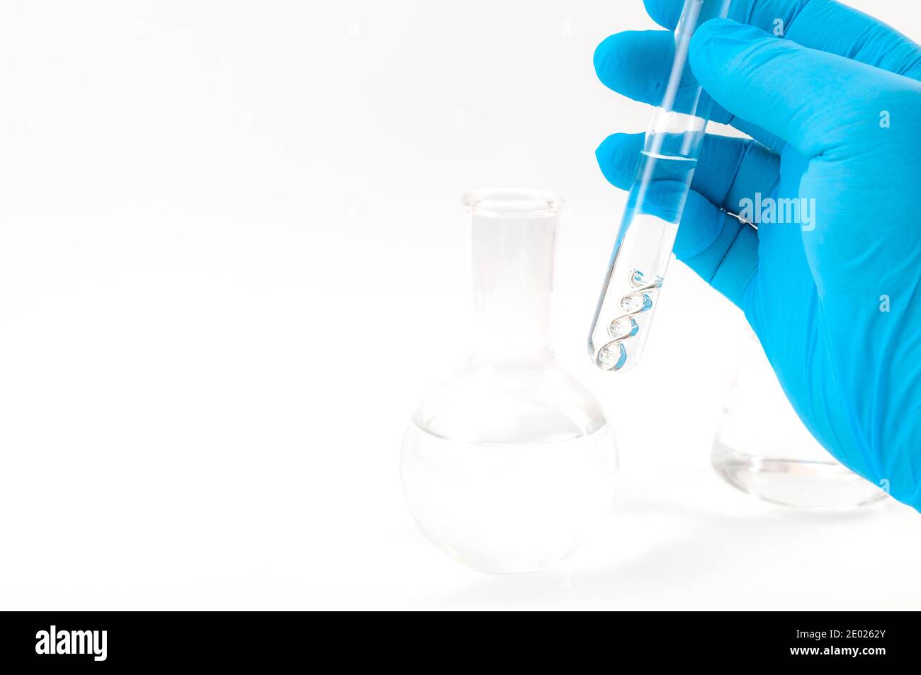 DNA testing, lab experiment and genetic research concept theme with a scientist holding a double helix molecule in a test tube with blue latex gloves Stock Photo