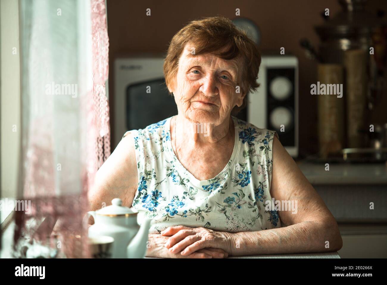 Portrait of an elderly retired woman sitting at a table Stock Photo - Alamy