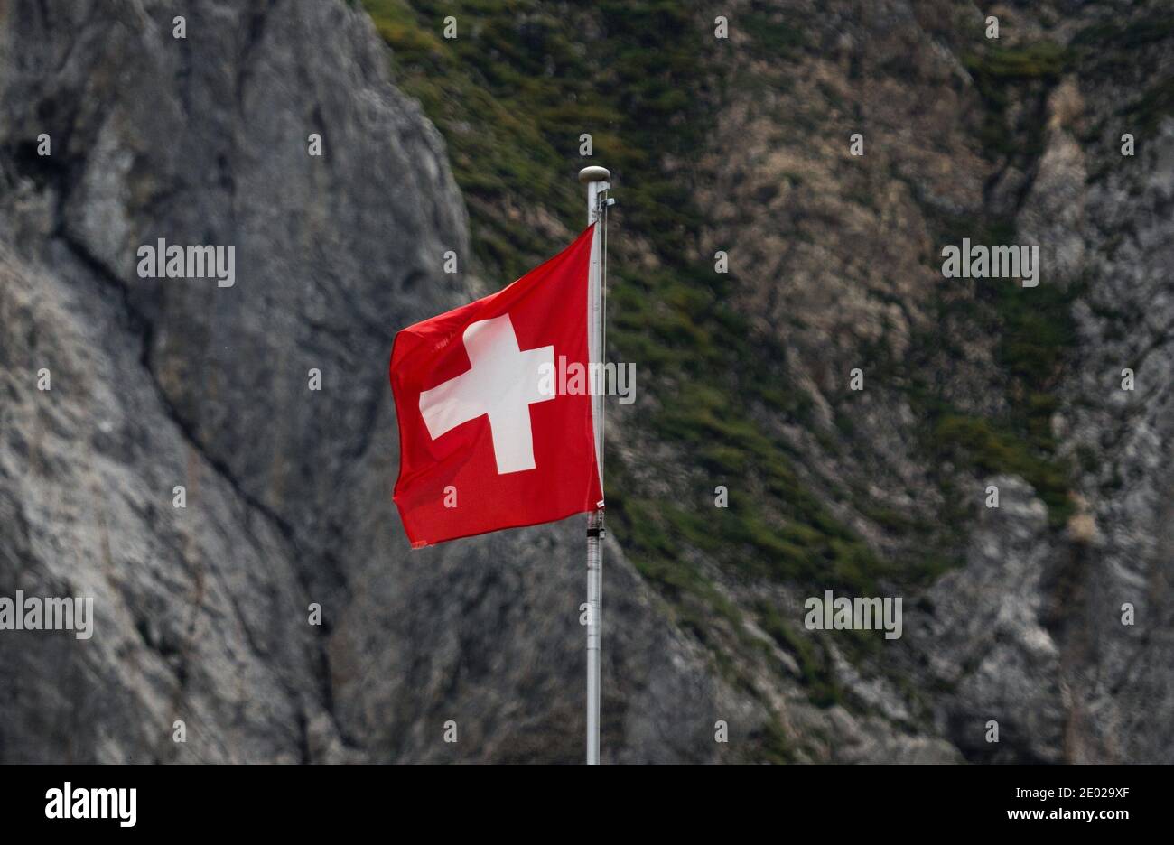 Swiss flag waving in the wind in Alpstein mountains alpine rocky background Appenzell in Switzerland Stock Photo