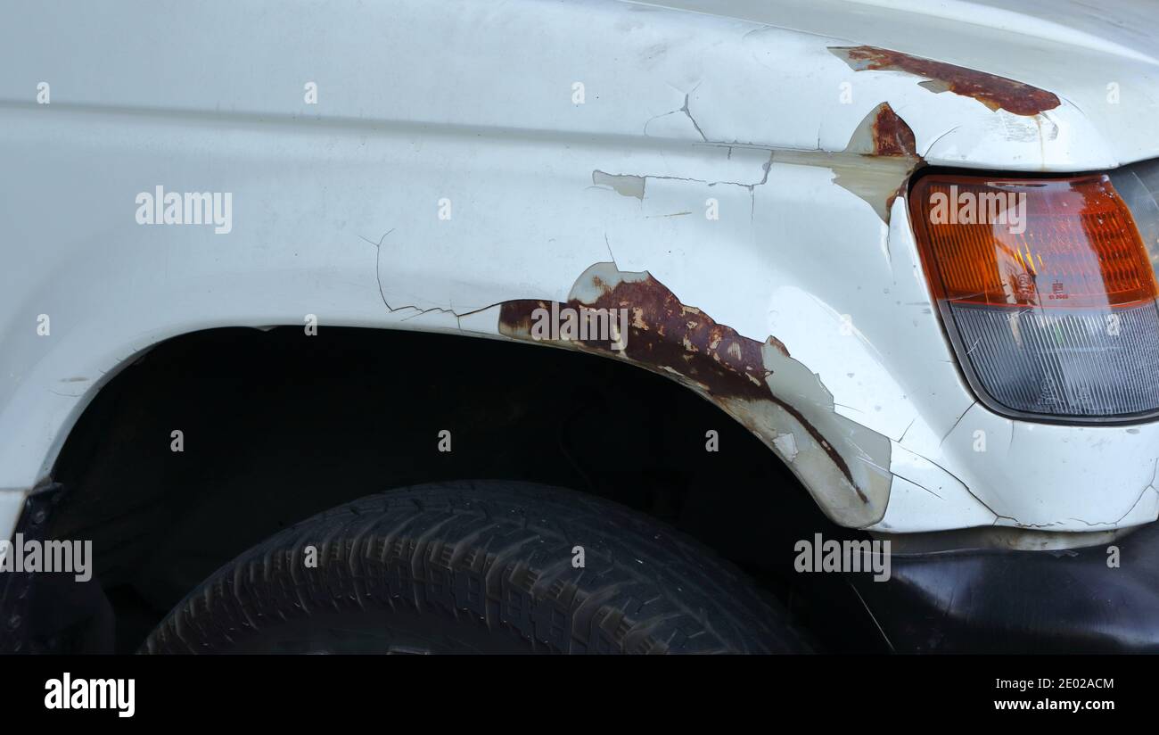 Damaged caused by scratch, peeling paint and rust at the front fender of a car Stock Photo