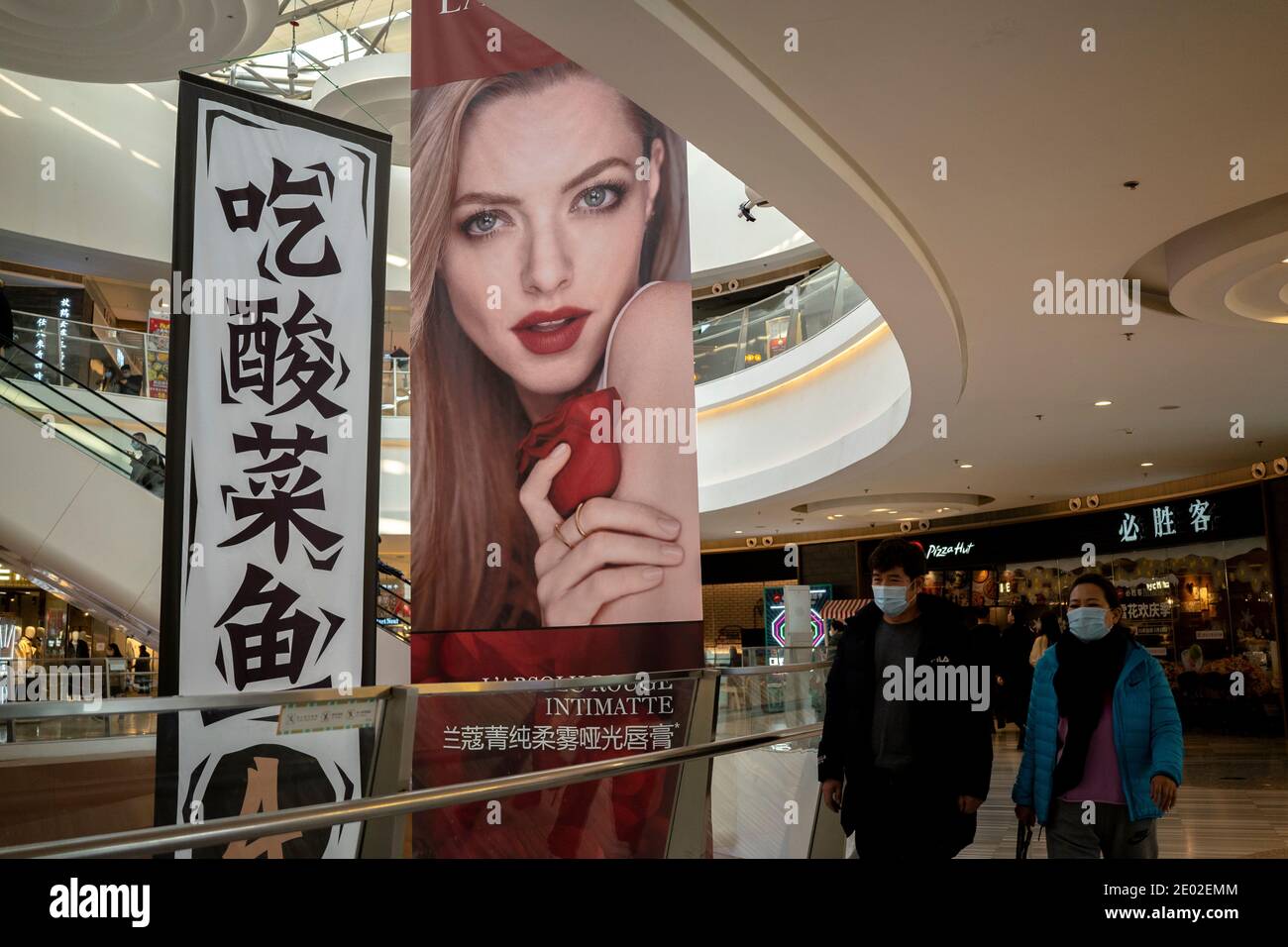 People, wearing face masks, are shopping in a shopping mall Stock Photo