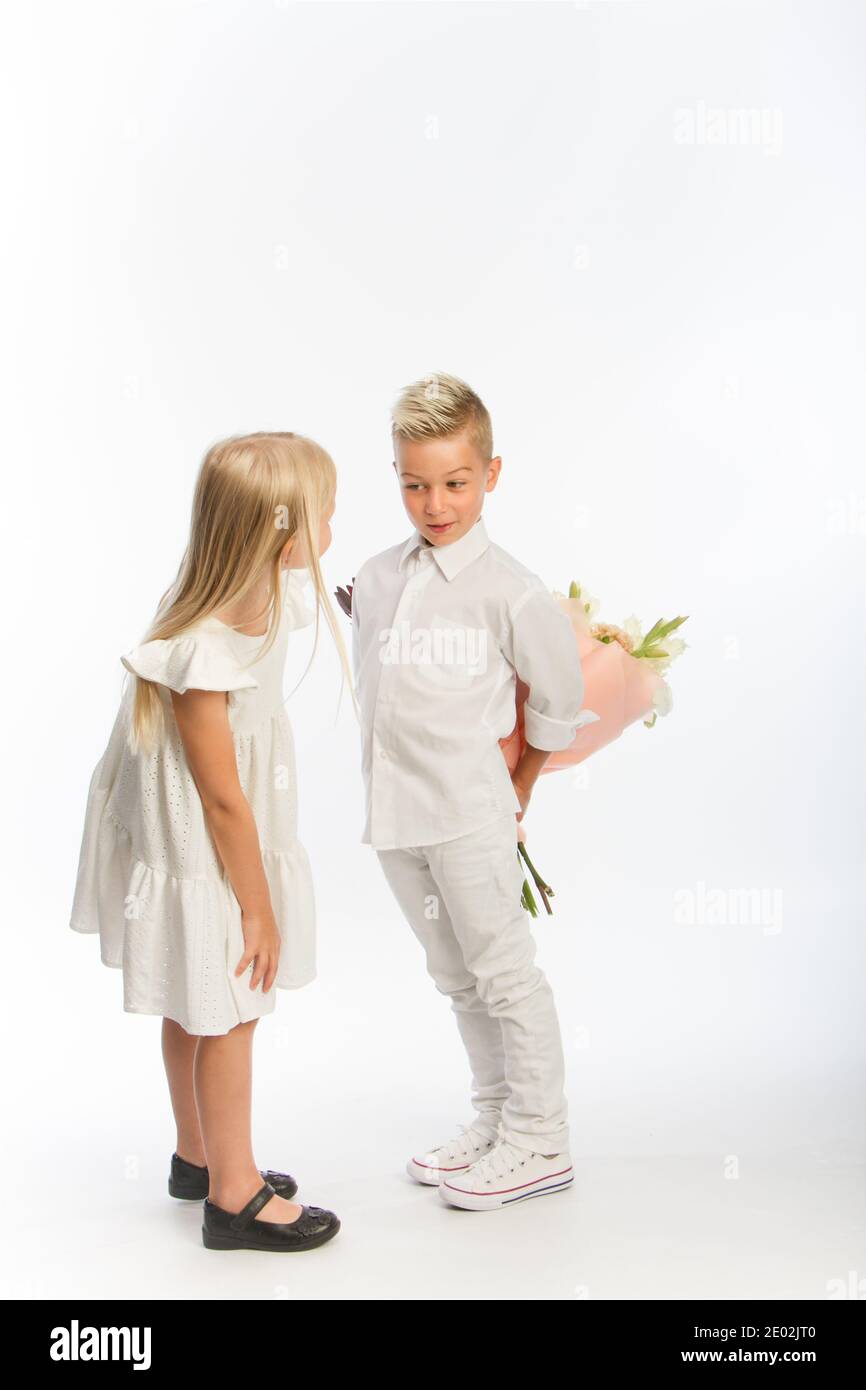 Studio portrait boy gives girl festive bouquet, congratulatory concept, white backdrop, copy space Stock Photo