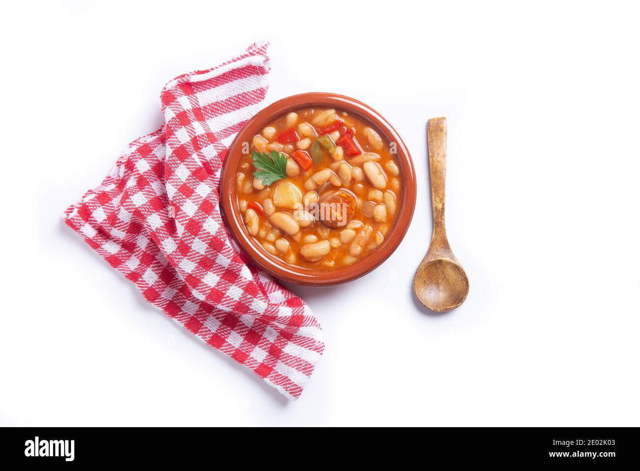 Traditional Spanish dish of beans stew with chorizo and potatoes, on white background.Top view. Stock Photo