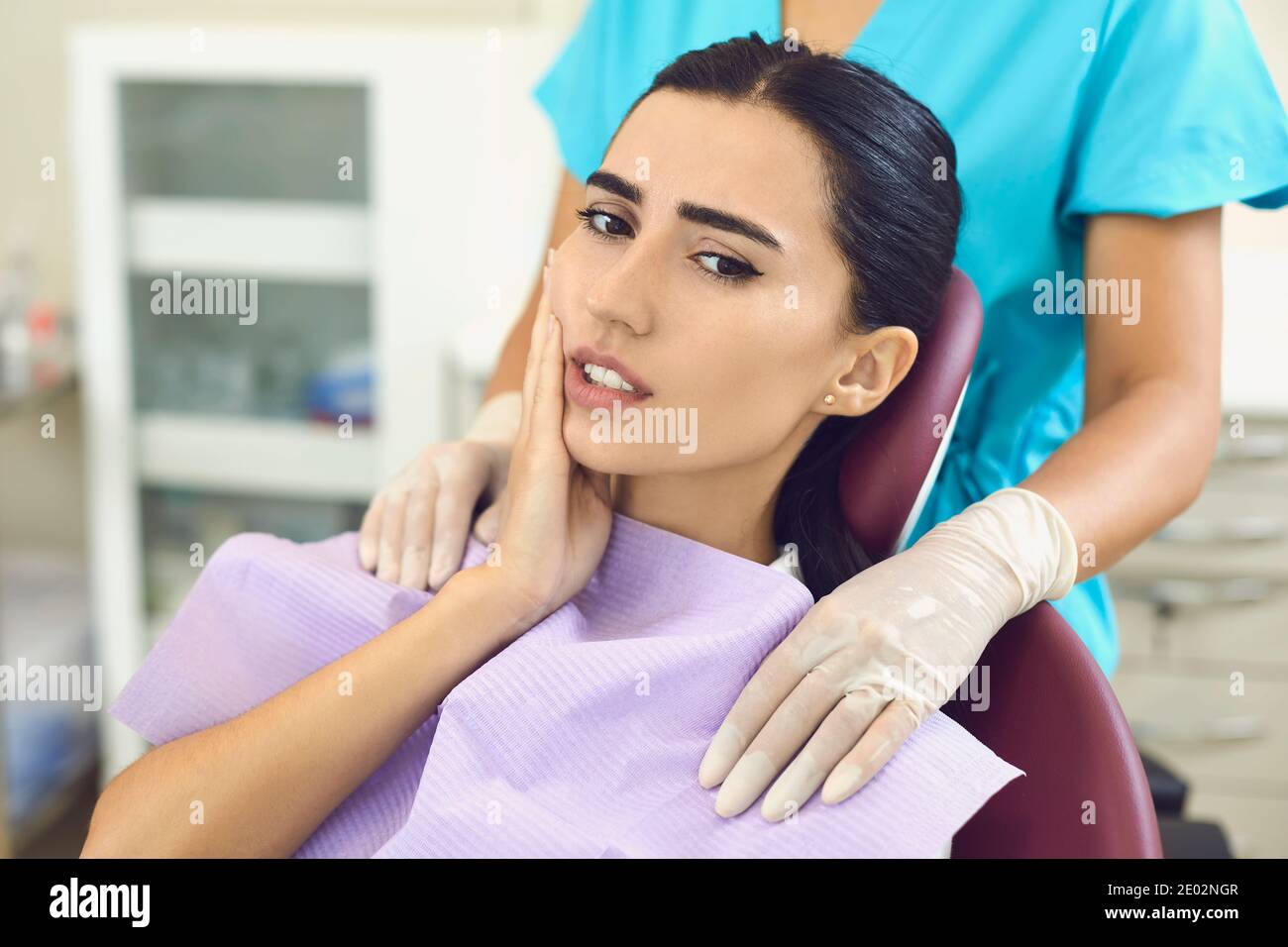 Woman patient feeling toothache touching cheek in dental clinic Stock Photo