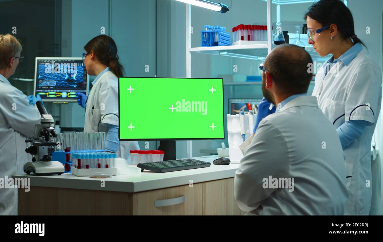 Team of microbiologists researching using computer with green screen ...