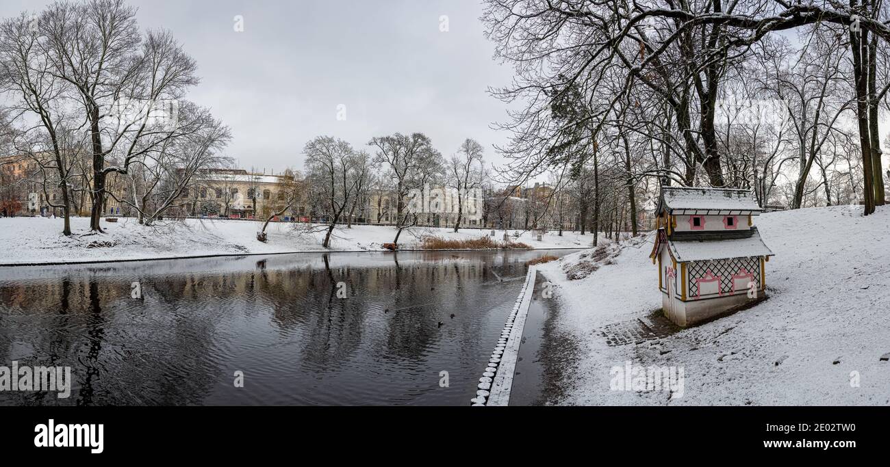 Panoramic winter landscape with snow in park with canal in Riga, Latvia. View of small house for birds snow covered park. Stock Photo
