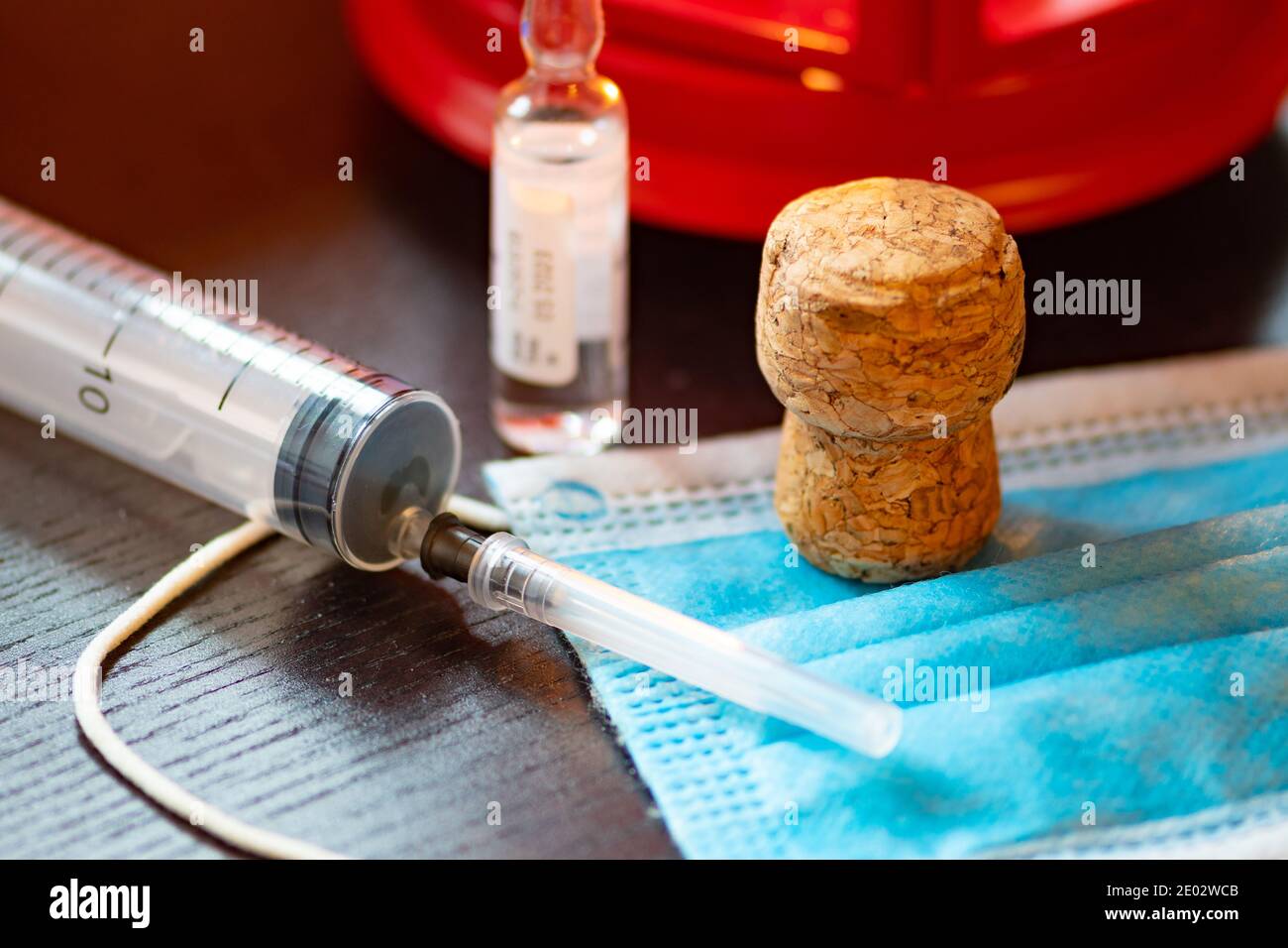 Syringe, vial, surgical face mask and cork. New year concept during Covid19 or Coronavirus emergency, no party Stock Photo