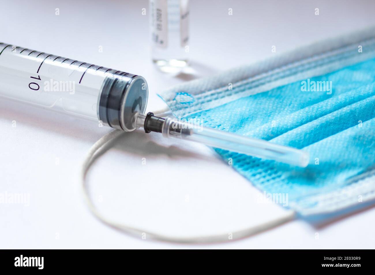 Syringe, vial and surgical face mask on a white table. Covid or Coronavirus vaccine background Stock Photo