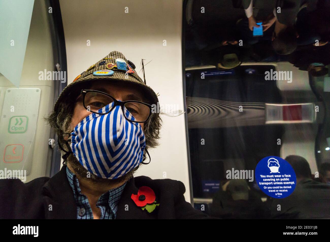 Selfie self-portrait of a  middle aged man wearing face mask on London Underground train showing face covering warning sign during Covid-19 pandemic Stock Photo