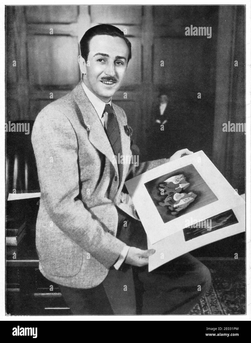 WALT DISNEY Portrait holding Animation Artwork publicity for WALT DISNEY's SNOW WHITE AND THE SEVEN DWARFS 1937 supervising director DAVID HAND story Jacob and Wilhelm Grimm  Walt Disney Productions / RKO Radio Pictures Stock Photo