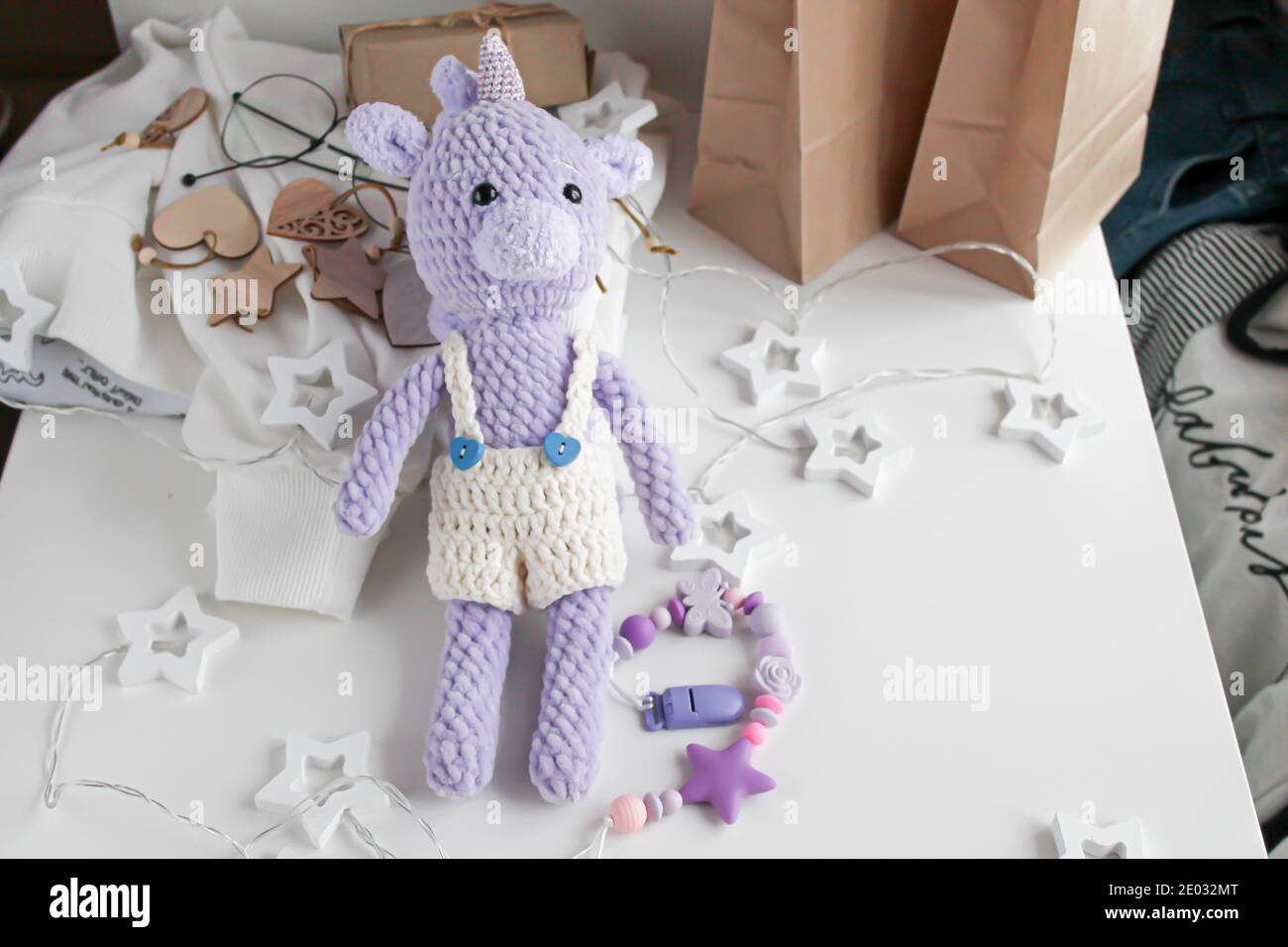 Purple knitted unicorn toy in white shorts lies on the table Stock Photo