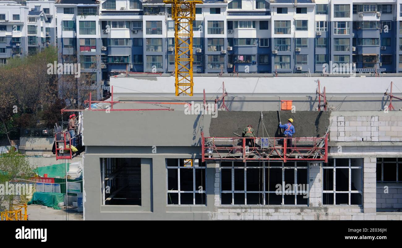 Asian construction workers on shelves outside the building, exterior paint and construction Stock Photo