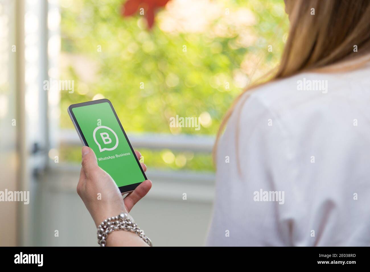 ROSARIO, ARGENTINA - DECEMBER 29, 2020: Whatsapp Business application logo on mobile phone screen held by young businesswoman's hand. Stock Photo