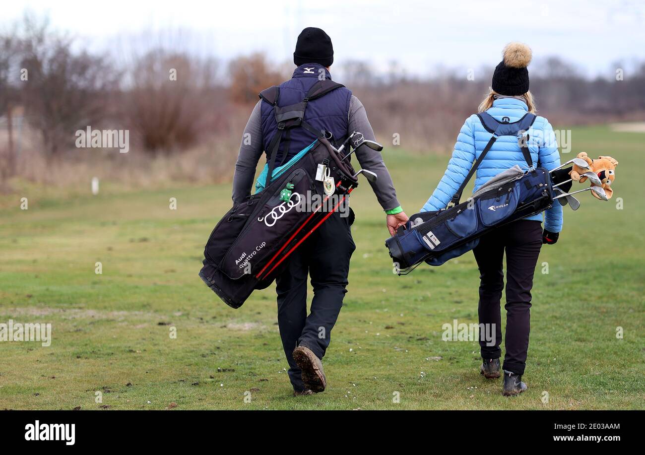 Magdeburg, Germany. 29th Dec, 2020. A couple walks around the grounds of  the Magdeburg Golf Club with golf equipment. Individual sports generally  remain permitted. On spacious grounds such as golf courses or