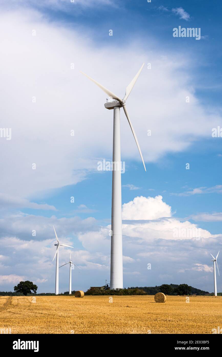 Windkraftanlagen auf einem abgeernteten Getreidefeld mit Wolken Stock Photo