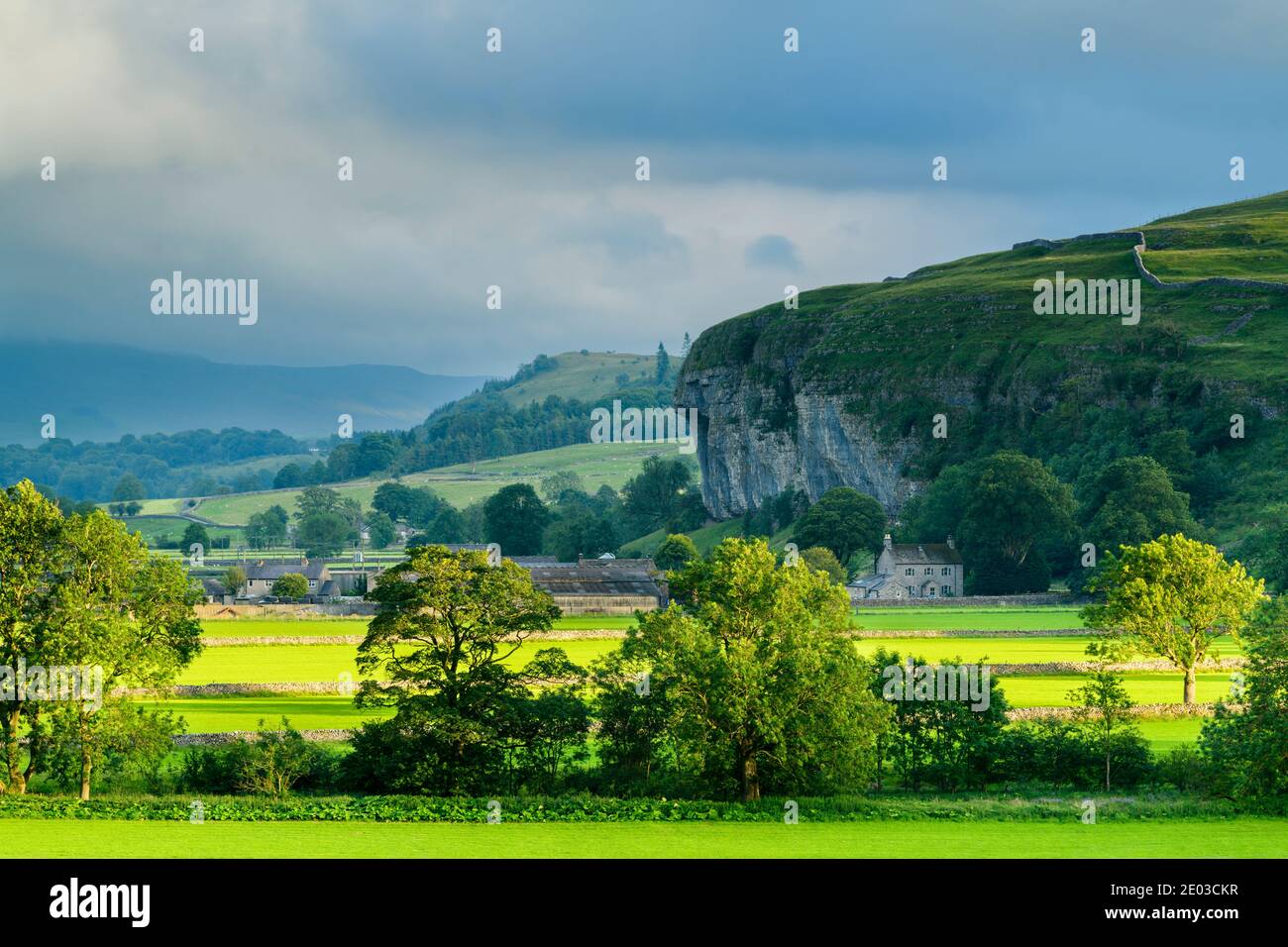 Scenic Wharfe Valley (flat sunlit fields, stone walls, Kilnsey Crag - high limestone cliff, rolling hills) - Wharfedale, Yorkshire Dales, England, UK. Stock Photo