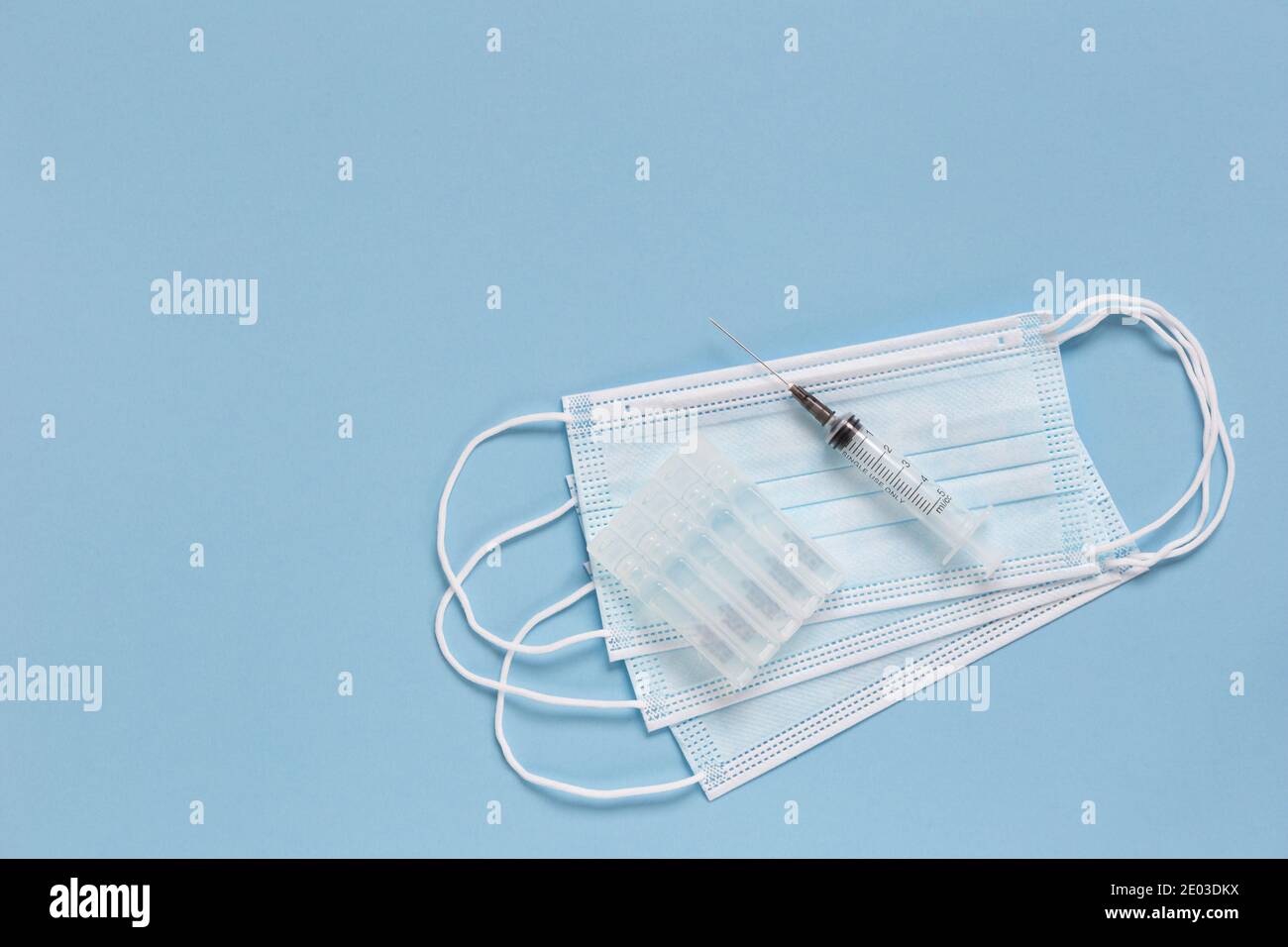 Protective face masks, ampullas with vaccine and expendable syringe for vaccination. Treatment from coronavirus infection and other diseases. COVID-19 Stock Photo